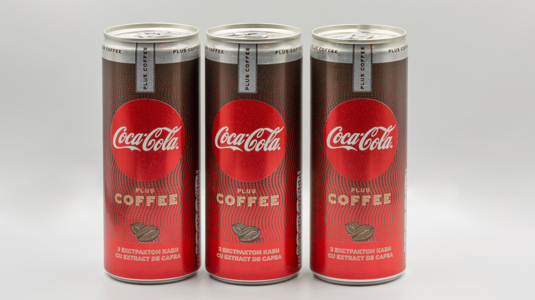 Three Coca-Cola Plus Coffee cans against a white background.