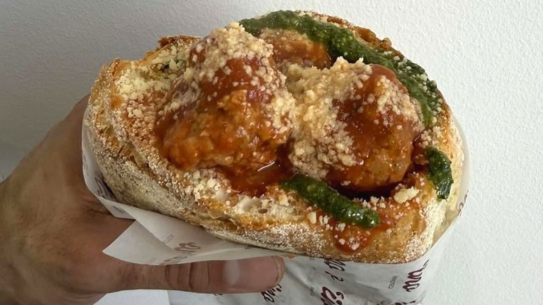 A hand holds a cuzzetiello sandwich