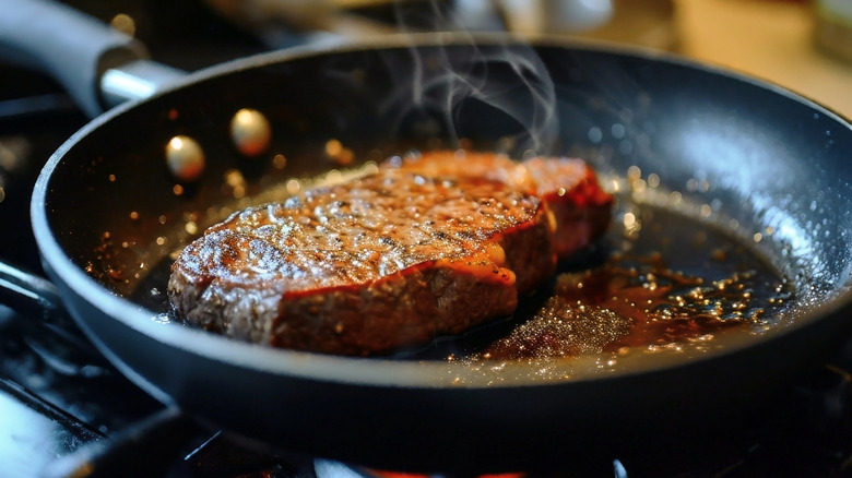 Steak being seared in frying pan