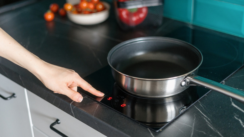 Person turning on stove, with pan on top