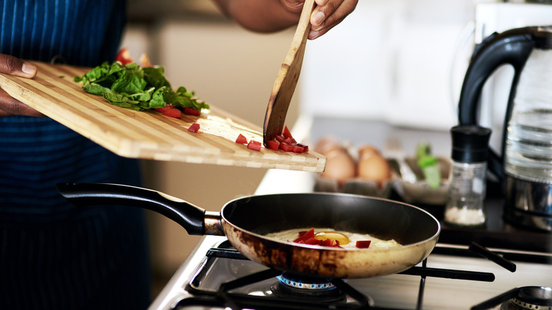 Person tipping ingredients into pan