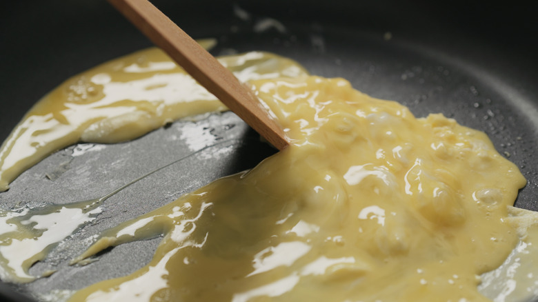 Person stirring scrambled eggs in nonstick pan