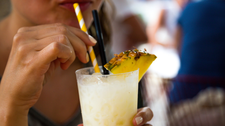 A close up of a person drinking a Piña Colada