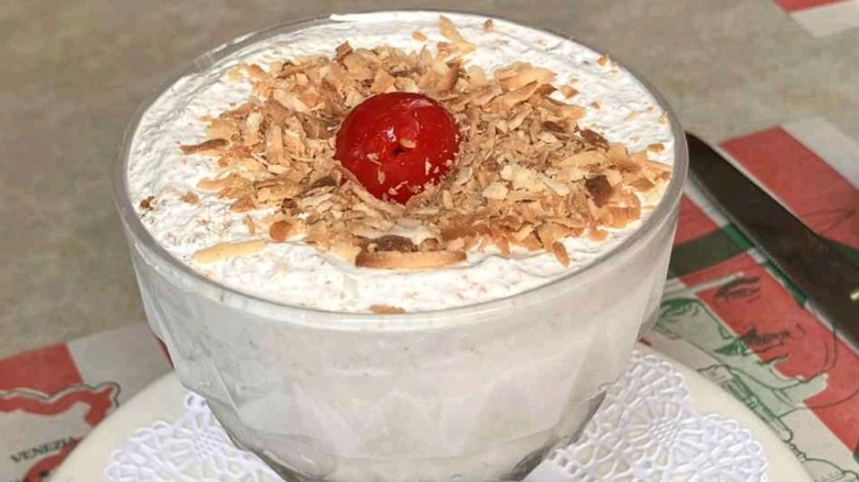 A bowl of tortoni topped with shredded coconut and a cherry