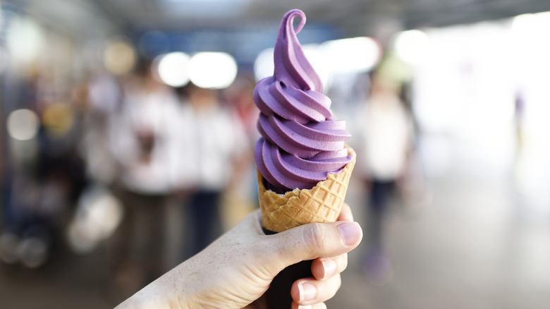 Close-up of a hand holding a cone of violet soft serve