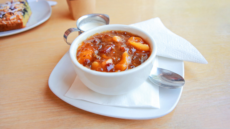 cup of scandinavian fruit soup on a saucer, at a cafe with coffee and pastry in the background