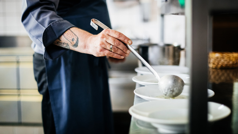 close-up of a chef ladling soup into bowls