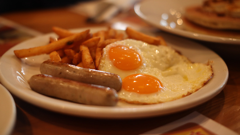 Denny's breakfast, with sausages, fried eggs, and fries