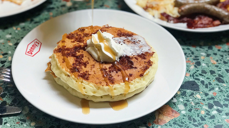 Plate of Denny's pancakes, with whipped cream and maple syrup