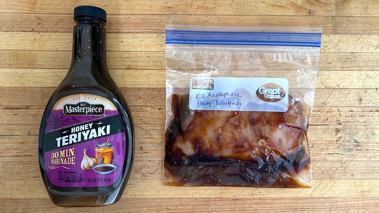 Bottle of K.C. Masterpiece Honey Teriyaki Marinade and bag with chicken marinating