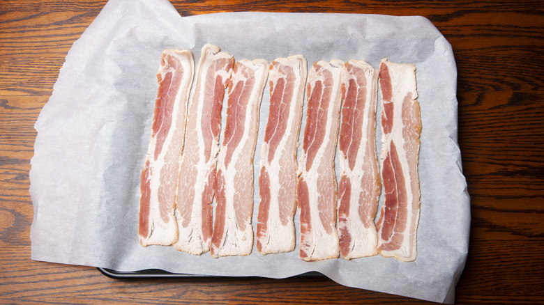 Raw bacon arranged on parchment paper