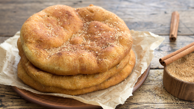 Stack of homemade fry bread on a plate dusted with cinnamon and sugar
