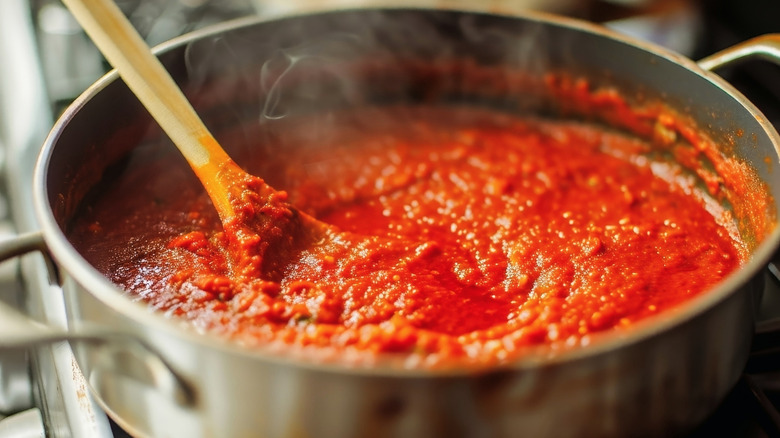 Tomato sauce simmering in a saucepan with a wooden spoon