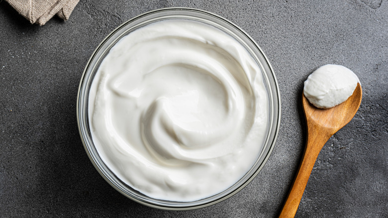 Greek yogurt in a bowl and a wooden spoon on the side