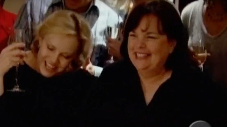 Ina Garten and a friend stand around a piano, smiling