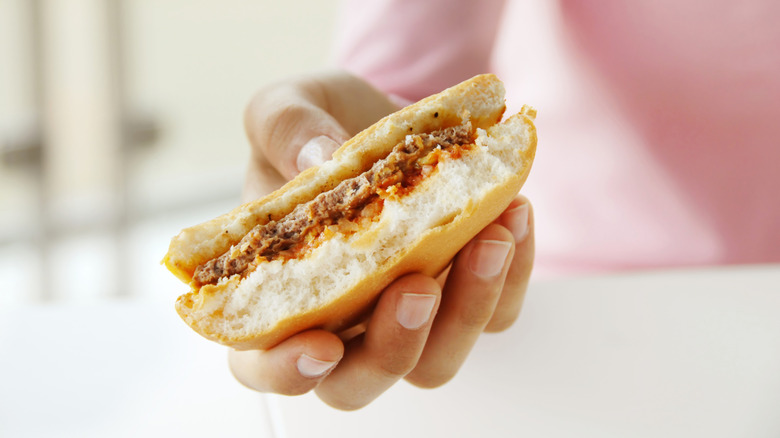 Person holding a half-eaten hamburger upside down