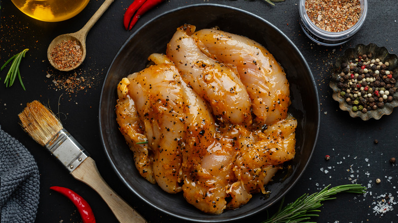 Chicken breasts marinating in a black bowl