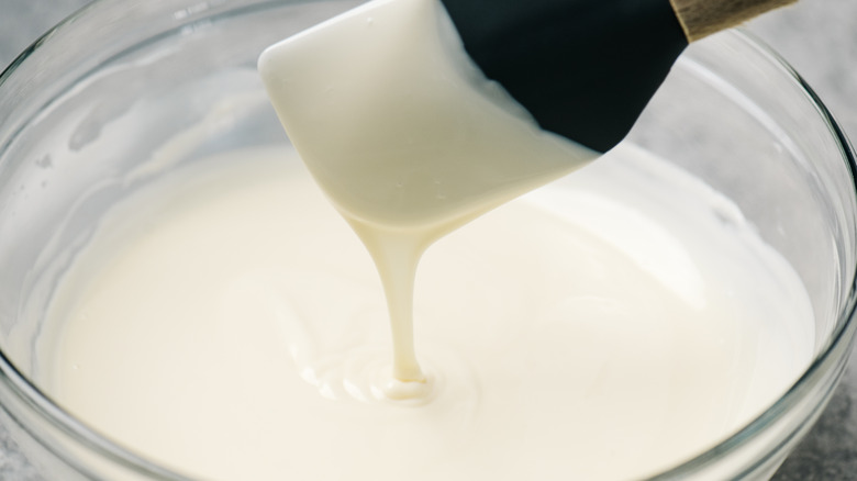 Evaporated milk in bowl, with spatula scooping it up