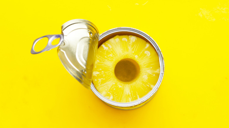 Open can of pineapple against a yellow background