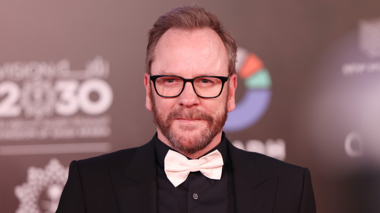 Kiefer Sutherland wearing a black suit with a white bow tie