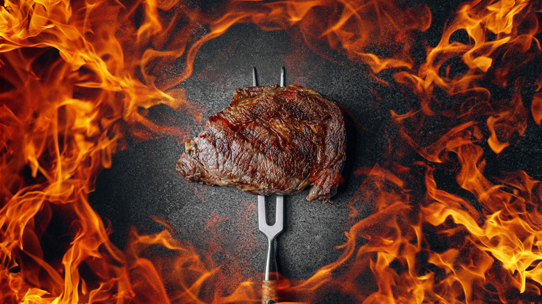 Steak on barbecue fork with fire