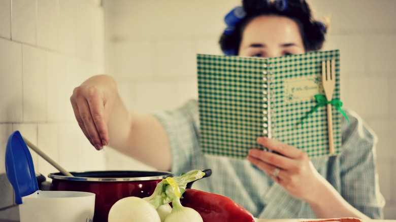 Woman reading recipe book and cooking