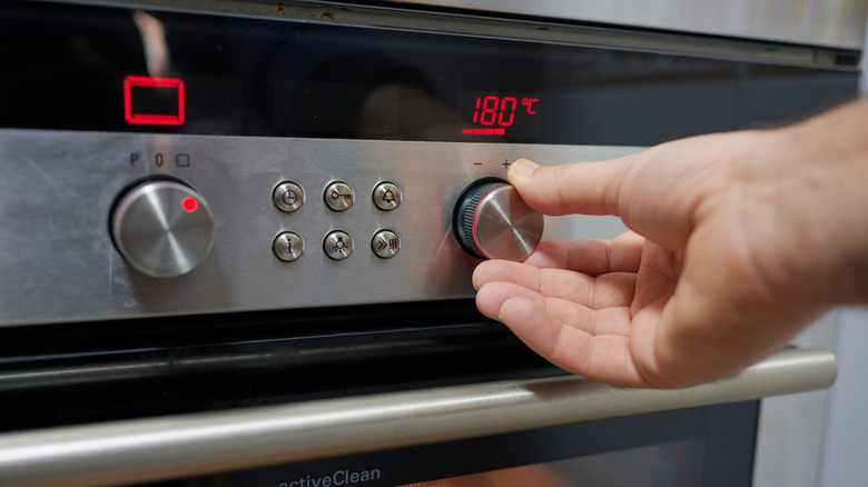 Person setting oven to 180 degrees Celcius