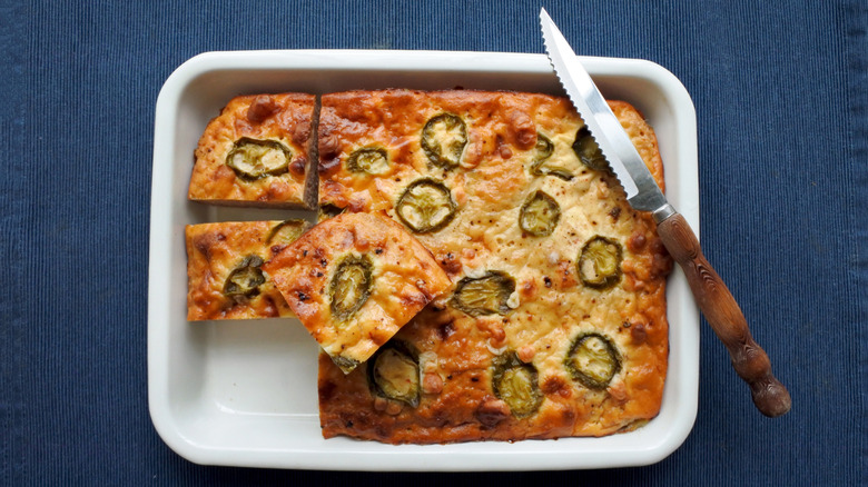 Cheesy jalapeño cornbread in a casserole dish with a knife