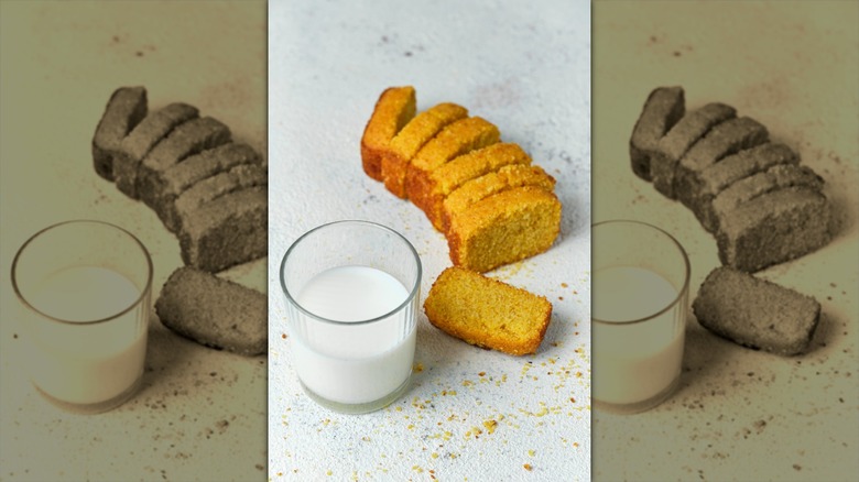 Cornbread and milk sitting on a white surface with crumbs