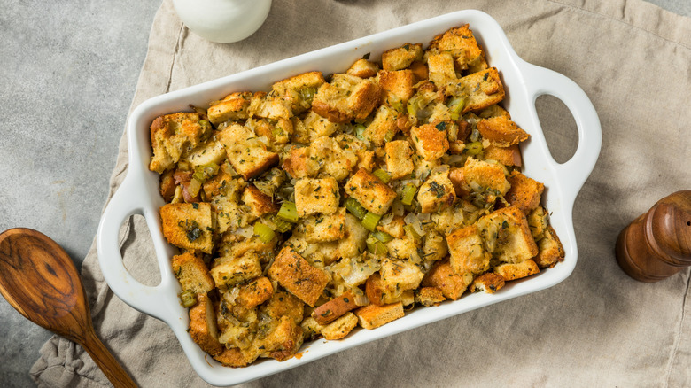 Cornbread dressing on a table next to a wooden spoon