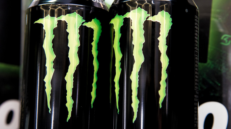 Two cans of Monster Energy original flavor