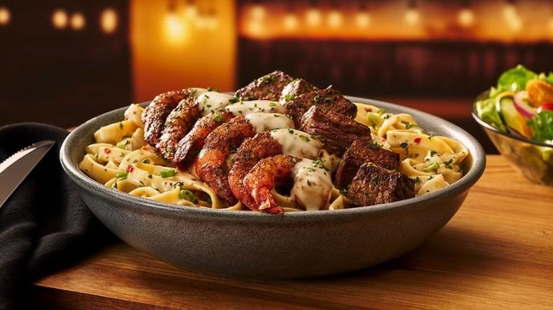 A steak and shrimp pasta served on a bowl at Outback Steakhouse