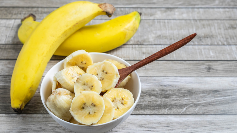 Fresh bananas sit next to a bowl of banana slices