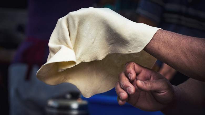 Close-up of pizza chef's hands catching a thrown piece of pizza dough