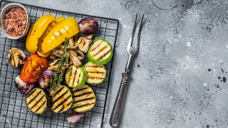 Grilled zucchini, peppers, onions, tomatoes, and mushrooms next to a serving fork