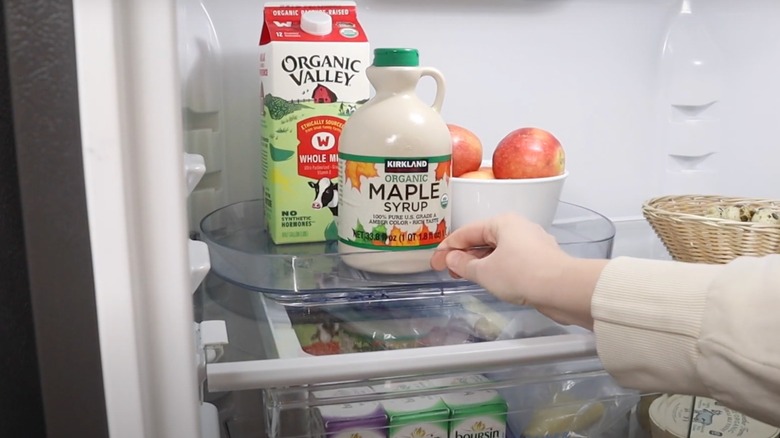 A hand holds a Lazy Susan in a refrigerator