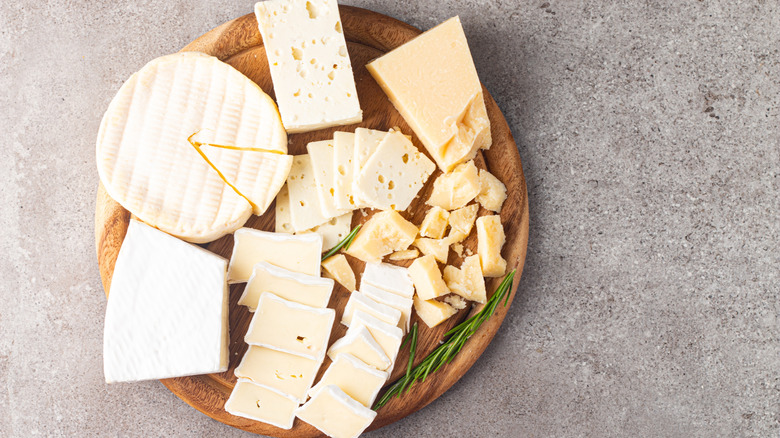 A wooden board covered in various cheeses