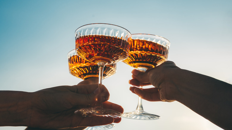 A group of people clink cocktail glasses