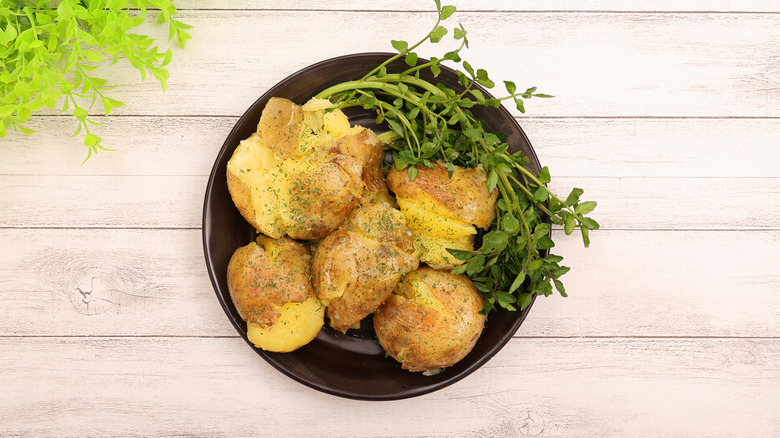 Bowl of smashed potatoes, garnished with watercress