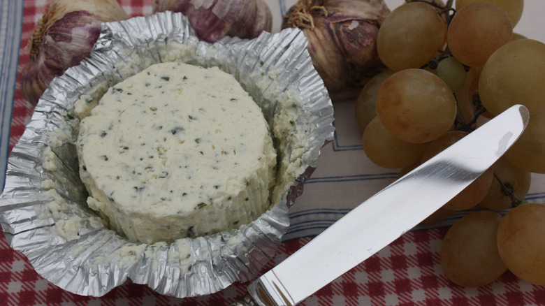 Open foil package of boursin with knife