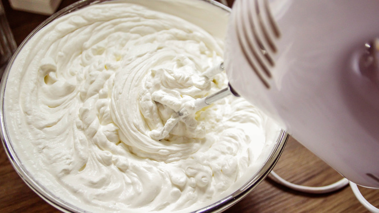 Bowl of whipped cream with hand mixer