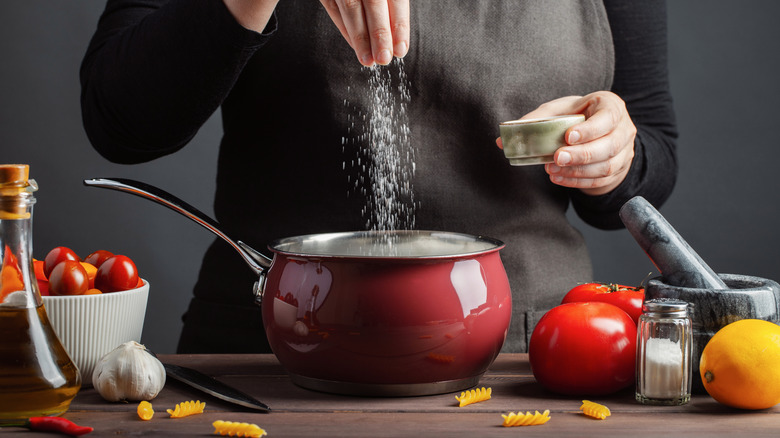 cook adding salt to pot