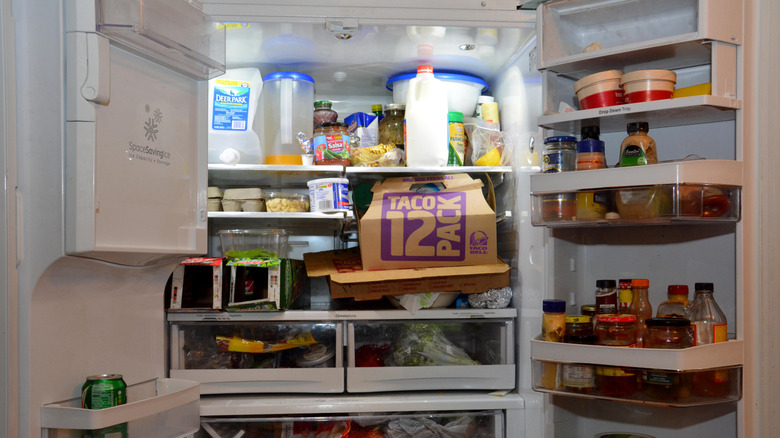 Condiments and food items cluttering the inside of an open fridge