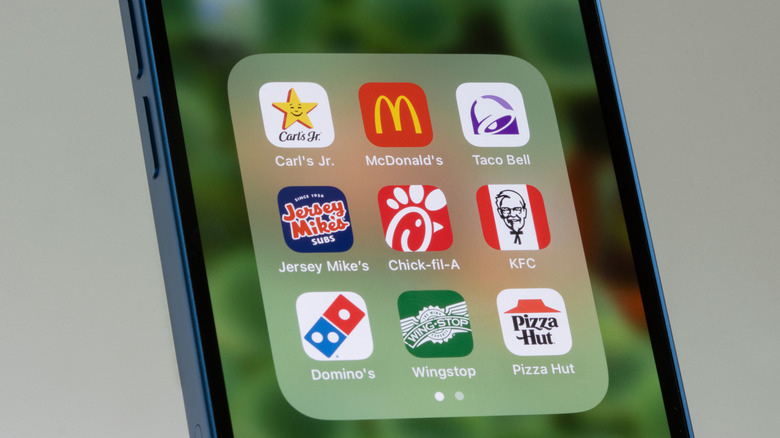 Assorted fast food apps are seen on a mobile phone screen, including Jersey Mike's, Domino's, Taco Bell, and Pizza Hut