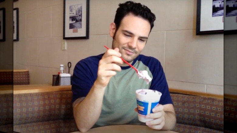 A man sits in a Dairy Queen, eating a Tripleberry Brownie Blizzard