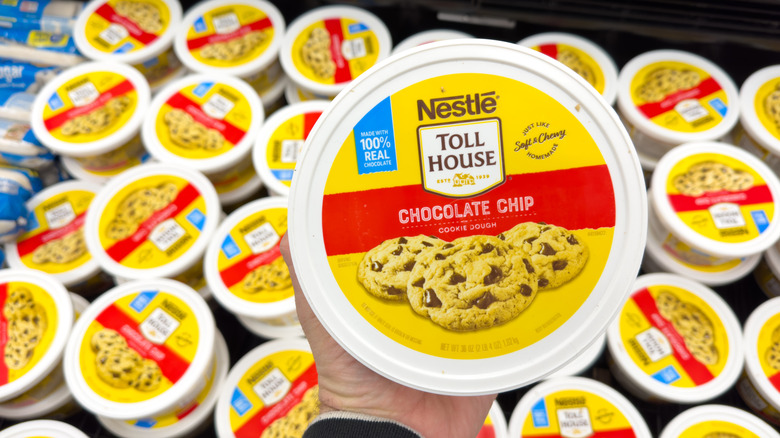 Person holding a tub of Nestlé Toll House Chocolate Chip Cookie Dough