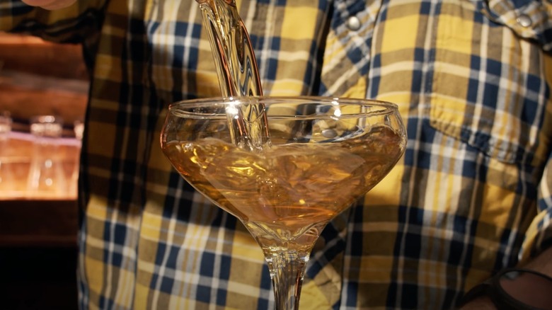 A bartender pours a Loaded Pistol cocktail