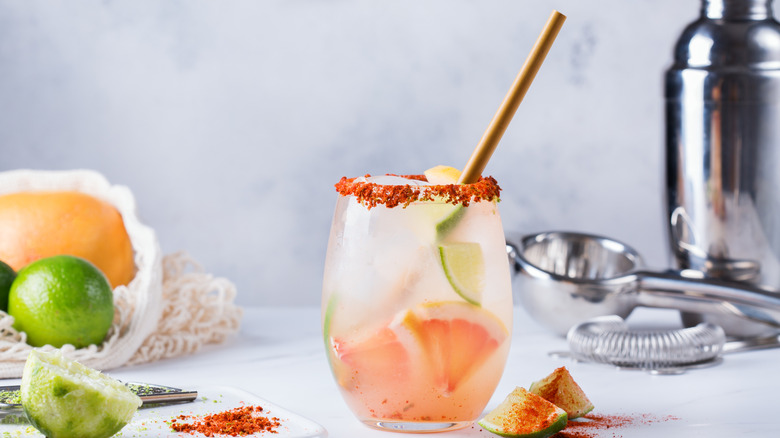 A mezcal paloma, surrounded by ingredients and cocktail equipment