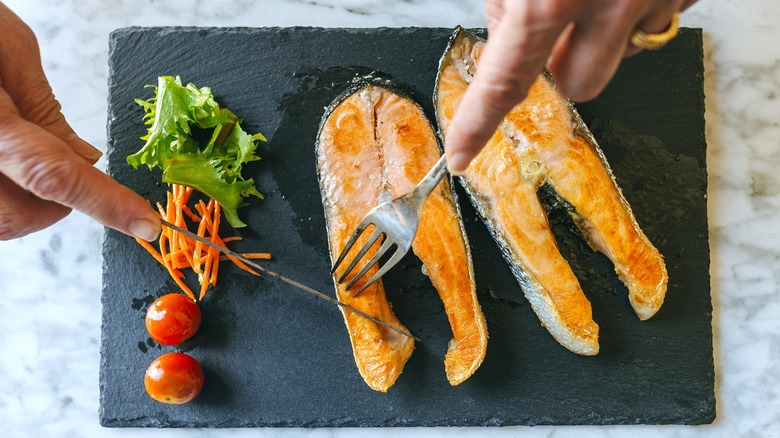 cutting into salmon fillets on black slate