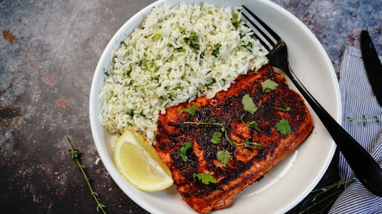 burnt salmon with rice on white plate